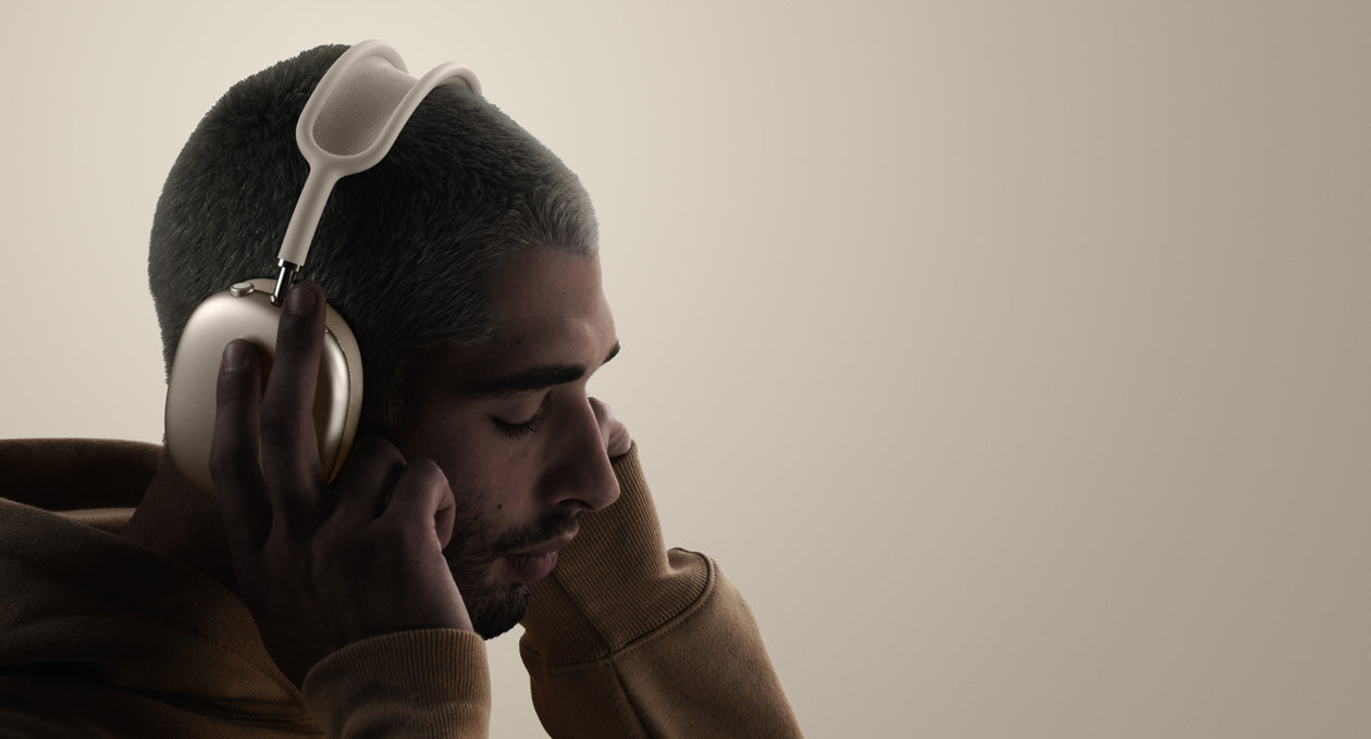 A person wearing AirPods Max 2 and touching an ear cushion.